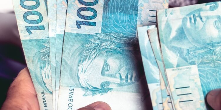 Notas de R$ 100 reiais nas mãos de uma pessoa.