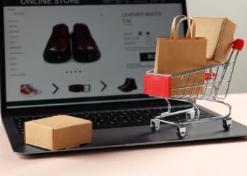 Notebook em um site de compra, com elementos que representam compras, como carrinho e embalagem.