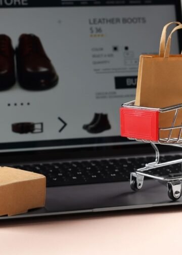 Notebook em um site de compra, com elementos que representam compras, como carrinho e embalagem.