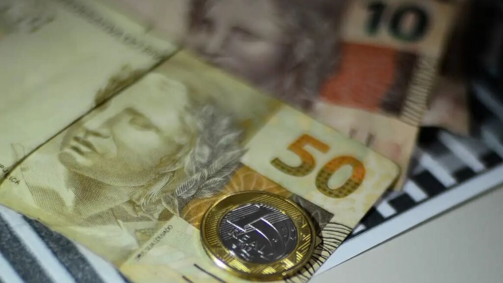 Notas de dinheiro e moeda de 1 Real.