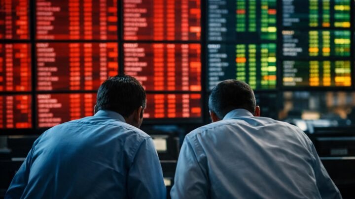 Painéis eletrônicos em ambiente de mercado financeiro exibem gráficos e